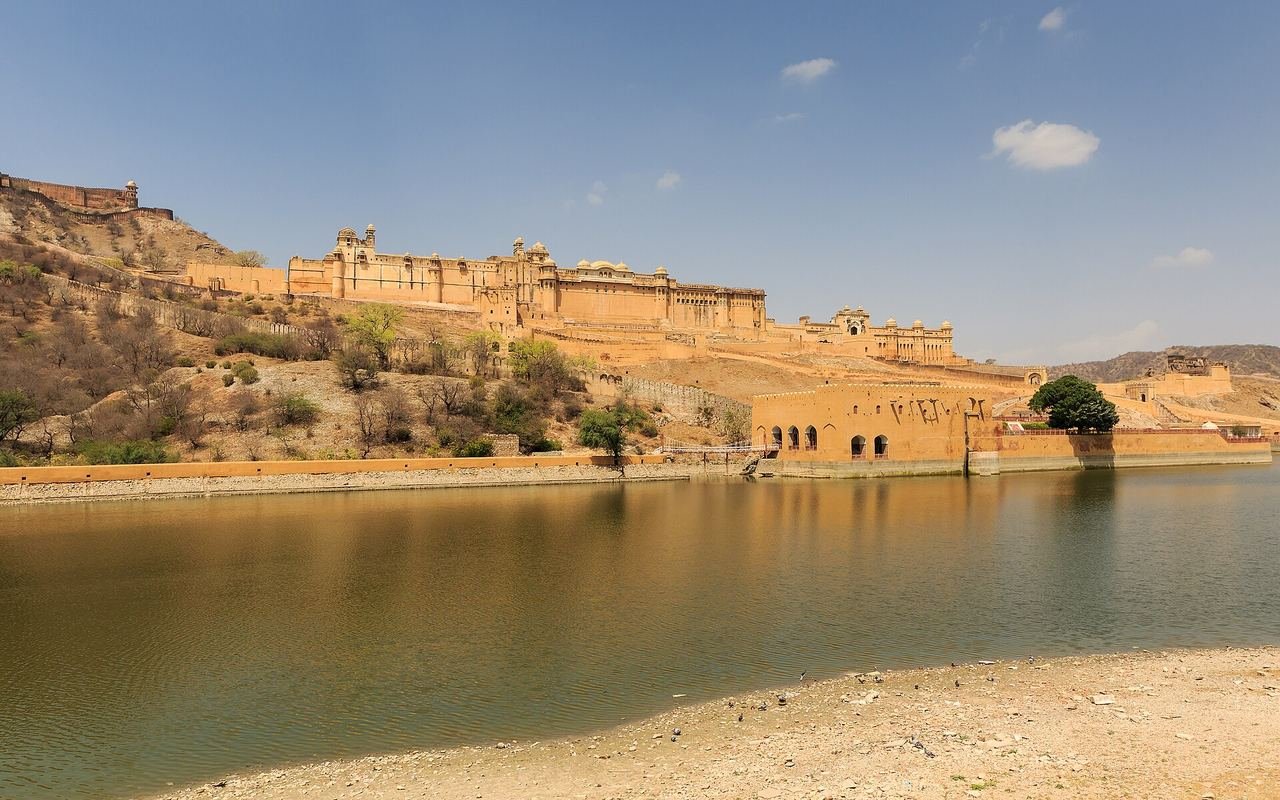 Amber Fort's sandstone walls and palaces on a hillside above the calm water of Maota Lake near Jaipur