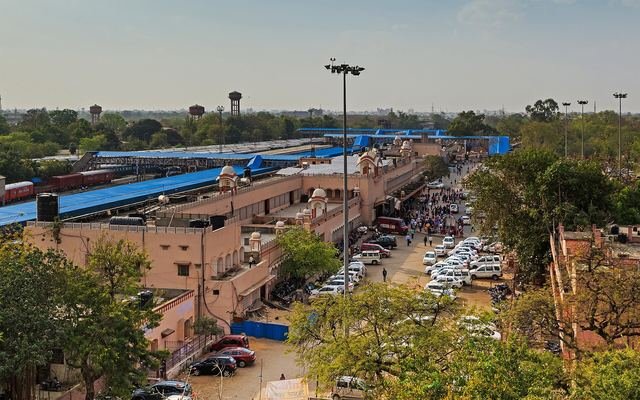 Elevated view of Jaipur railway station with blue platform roofs, station buildings and a busy car park